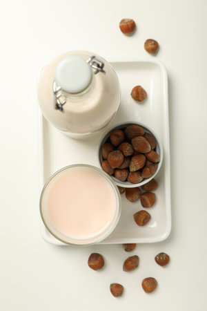 Bottle and glass with milk and bowl with nuts on white background, top viewの写真素材