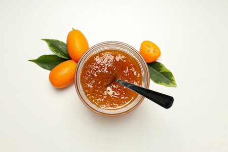 Fresh kumquat fruits and jar of jam with spoon on white background, top viewの写真素材