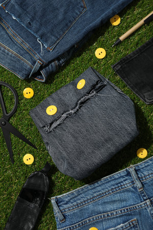 Denim bag and jeans on green background, top view
