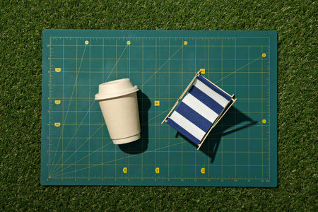 Drawing, paper cup and handmade figurine on green background, top view