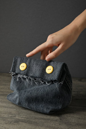 Handmade denim bag and hand on gray background