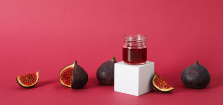 Figs and jar of jam on white block on pink backgroundの写真素材