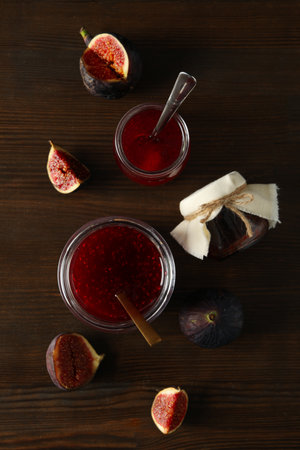 Figs and jars of jam on wooden background, top viewの写真素材