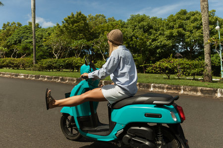 Young woman enjoys a ride on a scooter in a parkの写真素材