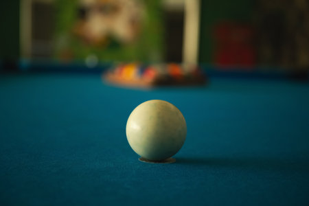 A white pool ball rests on a blue surface ready for the next shot