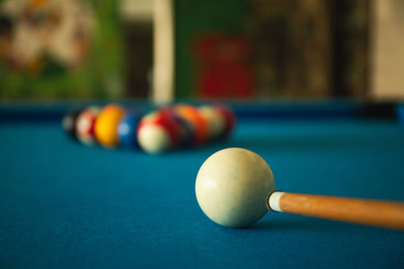 A cue is poised to strike the ball on a blue table