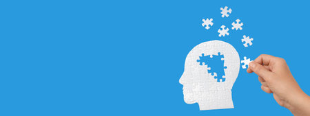 A hand inserts a puzzle piece into a head silhouetteの写真素材