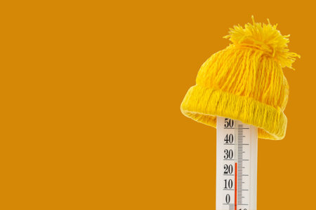 Cold weather represented by a thermometer with a warm hatの写真素材
