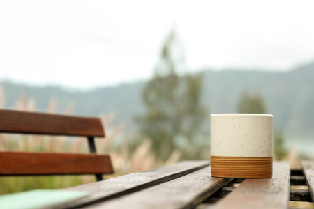 Enjoying a warm drink on a wooden table with lake viewsの写真素材