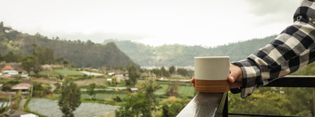 Holding a warm cup of coffee while enjoying scenic viewsの写真素材