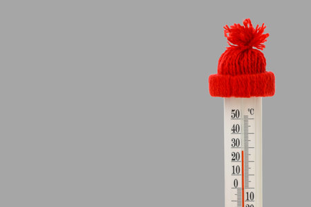 Thermometer shows low temperatures while wearing a warm hat