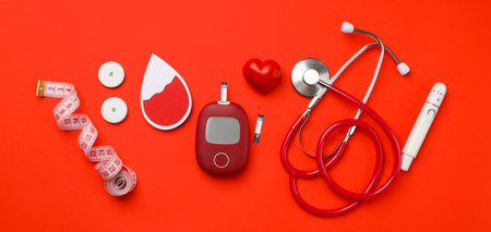 Diabetes supplies: glucose meter, stethoscope, tape on red backgroundの写真素材