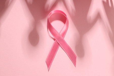 Pink ribbon placed on soft pink surface with gentle shadowsの写真素材