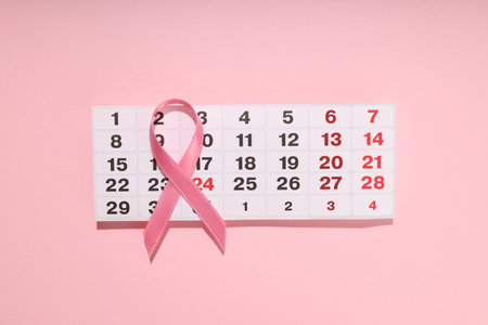 Pink ribbon placed on a calendar highlighting October datesの写真素材