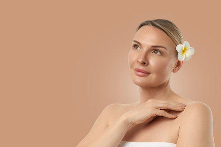 Woman calms herself, touching her shoulder, flower in hairの写真素材