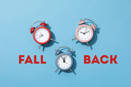 Three alarm clocks in red, pink, and blue on a blue backgroundの写真素材