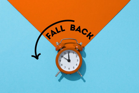 Vintage orange alarm clock placed against a blue backgroundの写真素材