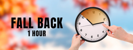 Hand adjusting clock to fall back one hour in autumnの写真素材