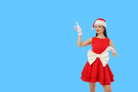 Woman in a red dress and Santa hat pointing with a smileの写真素材