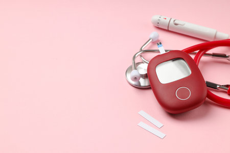 Blood glucose meter and stethoscope on pink surfaceの写真素材