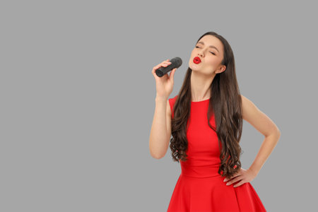Singer with long hair wearing a red dress holds a microphoneの写真素材