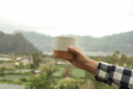 Person enjoys a warm drink while admiring the beautiful hillsの写真素材