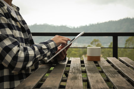 Person uses a tablet in a peaceful outdoor settingの写真素材