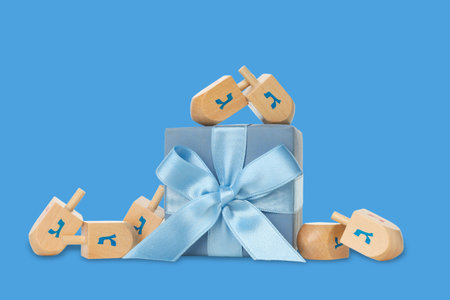 Dreidels circle a gift box tied with a blue ribbonの写真素材