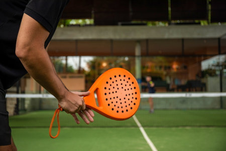 Player prepares to serve on padel court surrounded by greeneryの写真素材