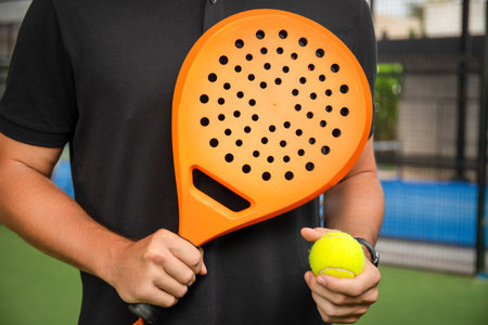 Player ready for padel with orange racket, yellow ballの写真素材