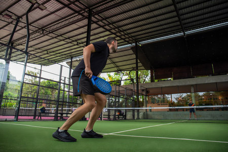 Player prepares for a shot on a green padel courtの写真素材