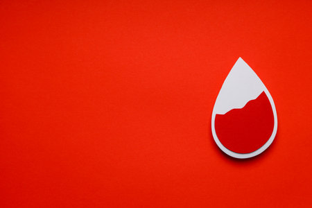 Red blood drop shape placed on bright orange backgroundの写真素材