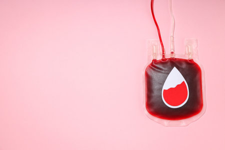 Blood donation bag with red liquid against a pink backdropの写真素材