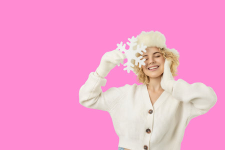 Woman smiling while holding a snowflake in soft winter attireの写真素材