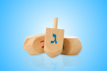 Three wooden dreidels with Hebrew letters resting against blueの写真素材