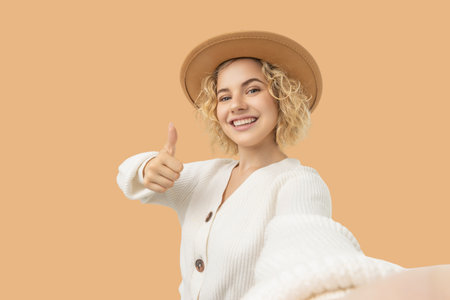 Young woman with curly blonde hair wearing a beige hatの写真素材