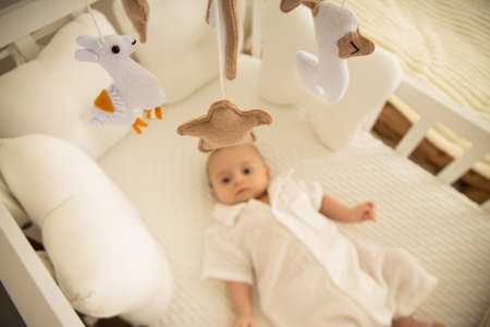 A serene baby resting in a cozy crib beneath soft toys