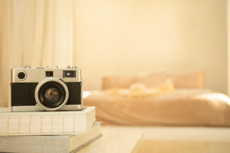A classic camera rests on a stack of books in a cozy bedroomの写真素材