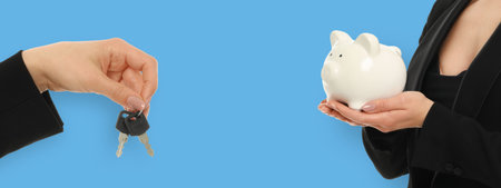 Two hands show keys and piggy bank on a blue backgroundの写真素材