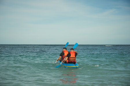 Two individuals are kayaking in calm waters on a sunny day