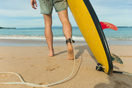 Surfer with a colorful board heads to the waterの写真素材