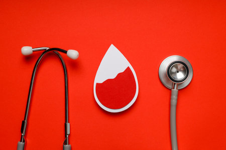 Stethoscope and red blood drop symbol on orange surfaceの写真素材