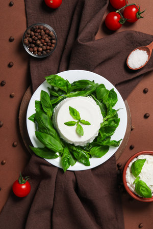 Basil, cheese, tomatoes, and spices are placed on a surfaceの写真素材