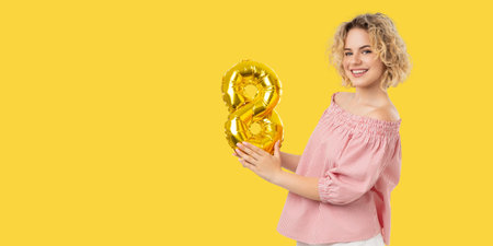 Woman smiles and holds a golden number balloon in celebration