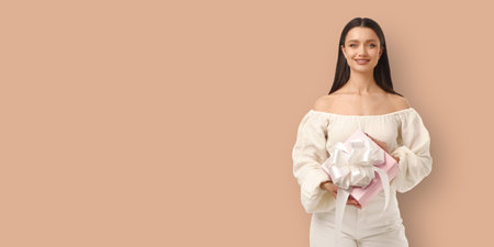 Woman stands with a gift and smiles in a festive settingの写真素材