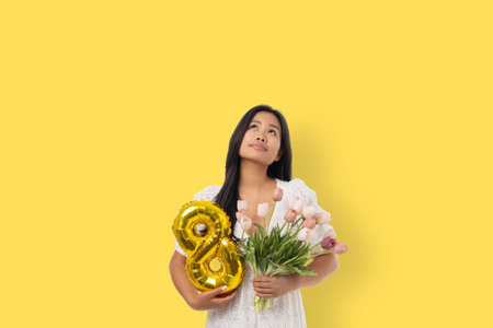 A young woman holds tulips and a balloon showing the number 8