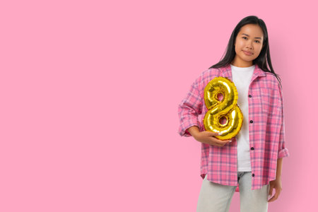 Young woman holds a golden balloon number 8 in spring