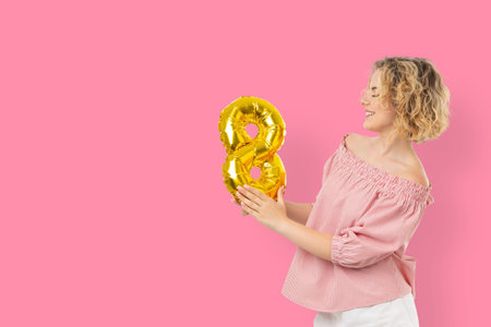 A woman holds a golden balloon shaped like the number 8