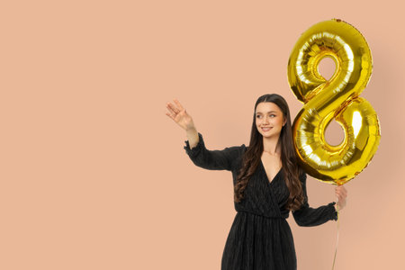 A young woman waves with a large number 8 balloon