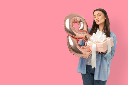 A young woman holds a present and a balloon showing the number 8
